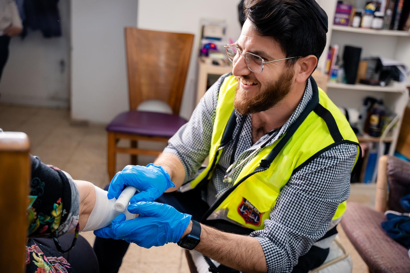 HatzBS volunteer bandaging a patient's arm at home